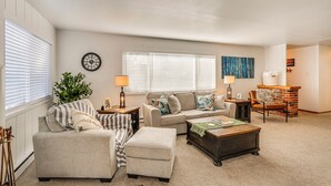 A living room with a sofa, ottoman, coffee table, and a fireplace. - 11 Mi to Burney Falls: Charming Home w/ Fireplace (Burney)