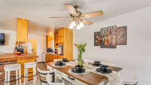 A modern kitchen with a wooden island, white bar stools, and a dining table set for six. - 11 Mi to Burney Falls: Charming Home w/ Fireplace (Burney)