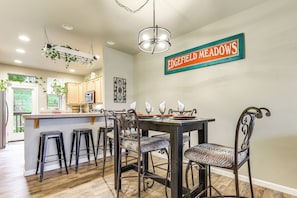 A modern kitchen with a bar area, wooden flooring, and a hanging plant. - Walk to Mcmenamins Edgefield: Inviting Townhome! (Troutdale)