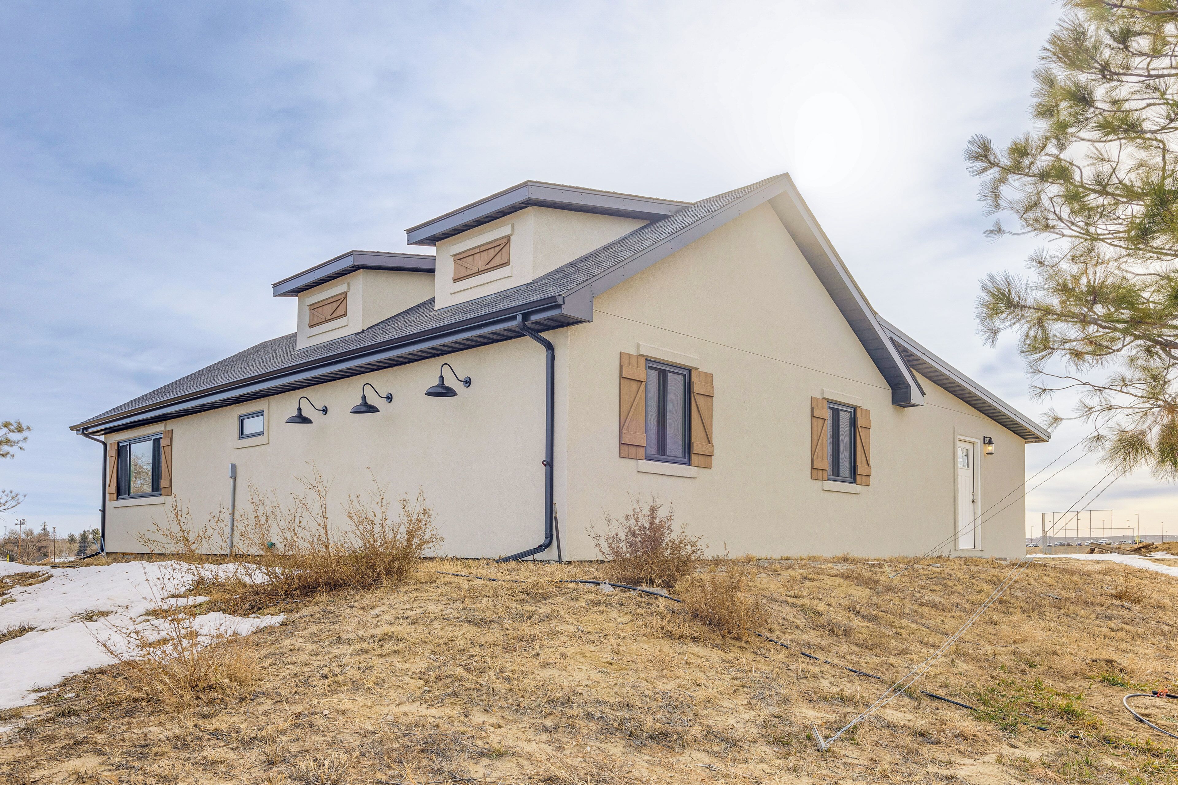 Ein eingeschossiges Haus mit geneigtem Dach, Schornstein und einer kleinen Veranda.