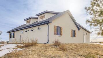 Ein eingeschossiges Haus mit geneigtem Dach, Schornstein und einer kleinen Veranda.