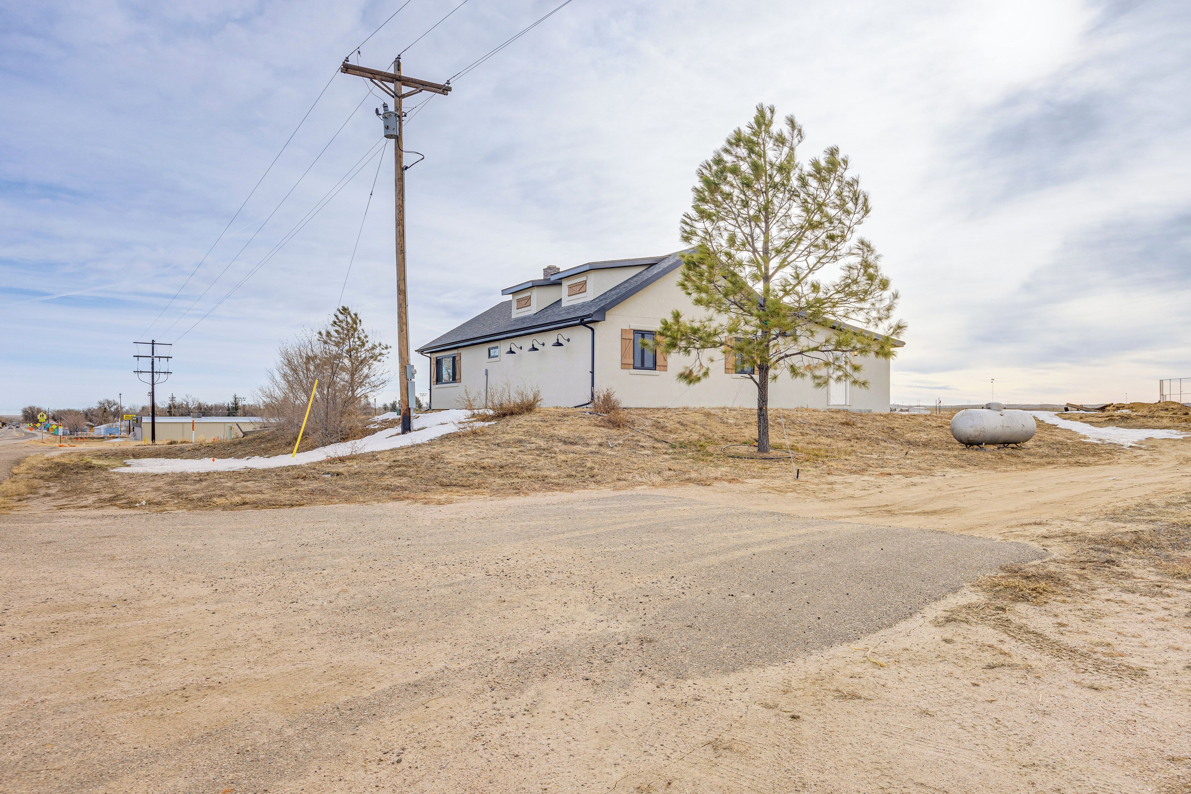 A single-story house with a sloped roof, a small porch, and a visible chimney. The surrounding area is a mix of dirt and sparse vegetation, with a large spherical object in the background.