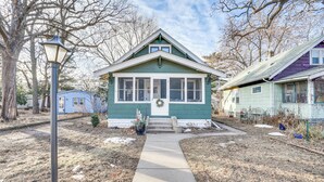 A green house with a front porch, a visible door, and a wreath on the door. - Walk to Beach + Lake Nokomis: Minneapolis Home! (Minneapolis)