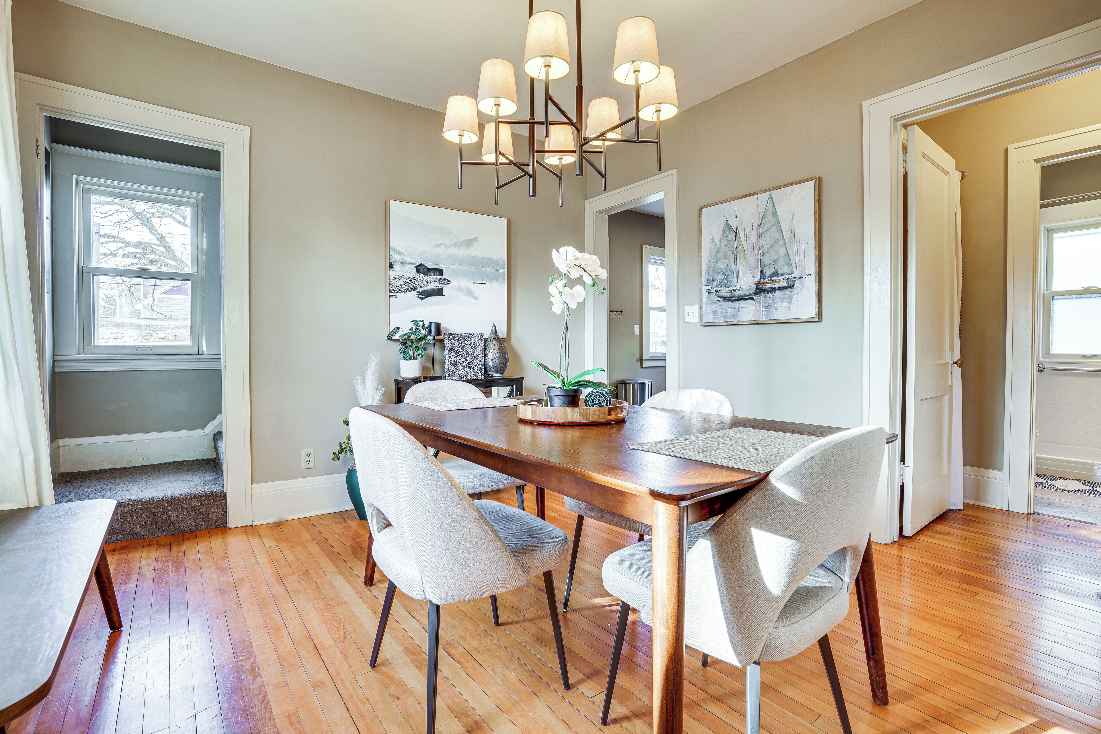 A dining area with a wooden table, four chairs, and a chandelier.