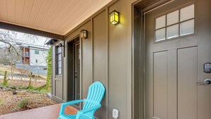 A porch with a blue Adirondack chair, a door with a window, and a wall-mounted light fixture. - Studio Apartment Near East Atlanta Village (Atlanta)