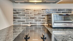 A modern kitchen with a built-in gas cooktop, a stainless steel toaster, and a backsplash with a brick pattern. - Studio Apartment Near East Atlanta Village (Atlanta)