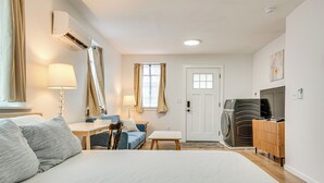 A hotel room with a large bed, a desk, a chair, a sofa, a washing machine, and a television. - Studio Apartment Near East Atlanta Village (Atlanta)