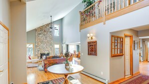 A spacious living area with a high ceiling, a stone wall, and a wooden staircase.