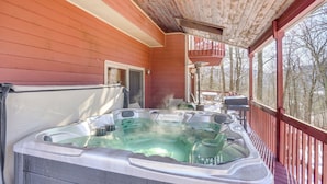 A hot tub on a wooden deck with a view of trees.