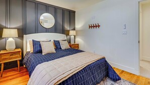 Ein Schlafzimmer mit einem großen Bett, zwei Nachttischen, einem Deckenventilator, einem Spiegel und einer Tür.