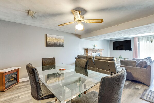 A modern living room with a glass-top dining table, leather sofas, and a ceiling fan. - 12 Mi to Dtwn St Louis: Family Home w/ Fireplaces! (Belleville)