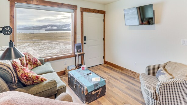 A living room with a large window, a flat-screen TV, and a wooden floor. - Starry Skies & Mtn Views: Family Retreat in Elmo (Elmo)