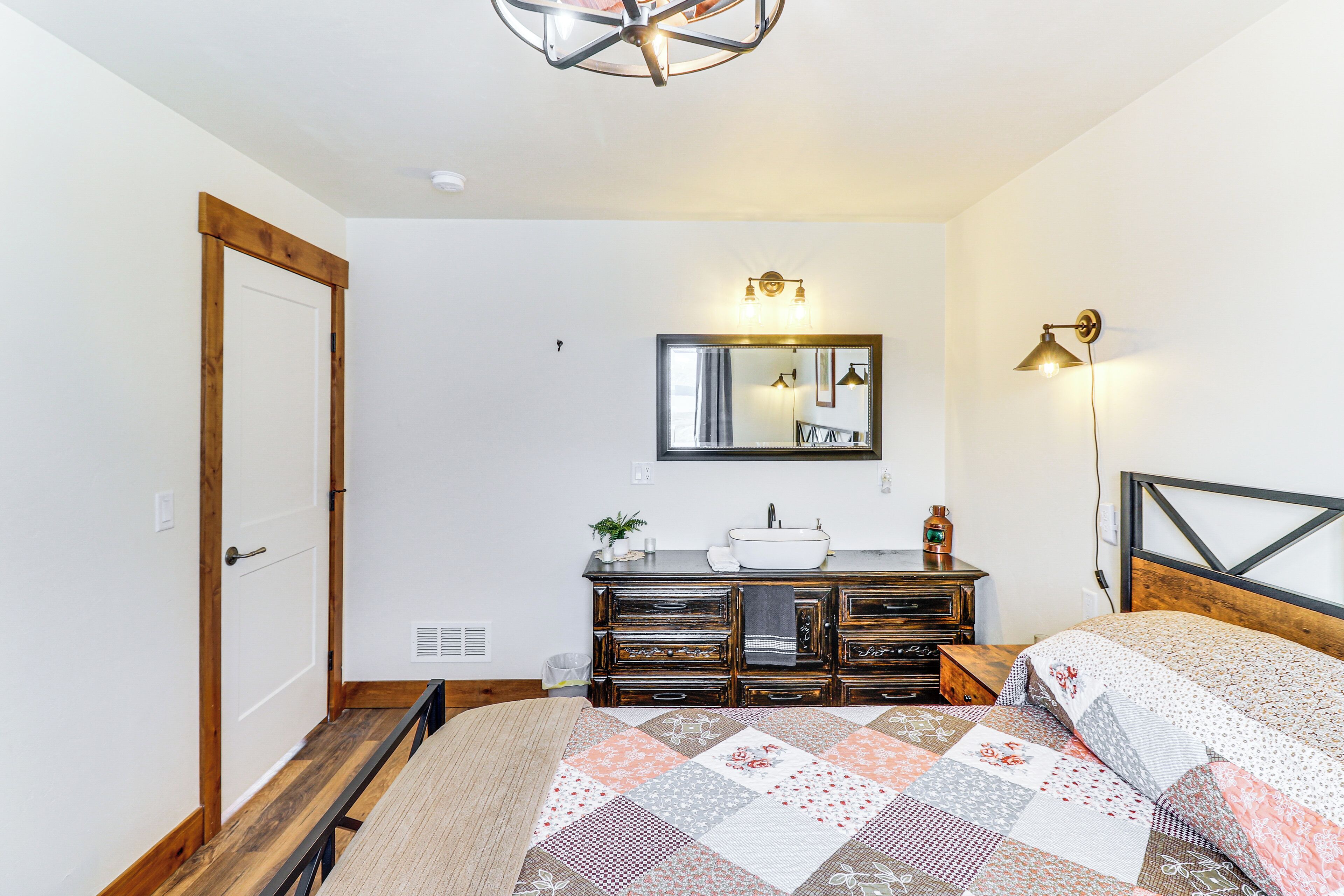 A bedroom with a wooden bed, a dresser, a mirror, and a bedside lamp.