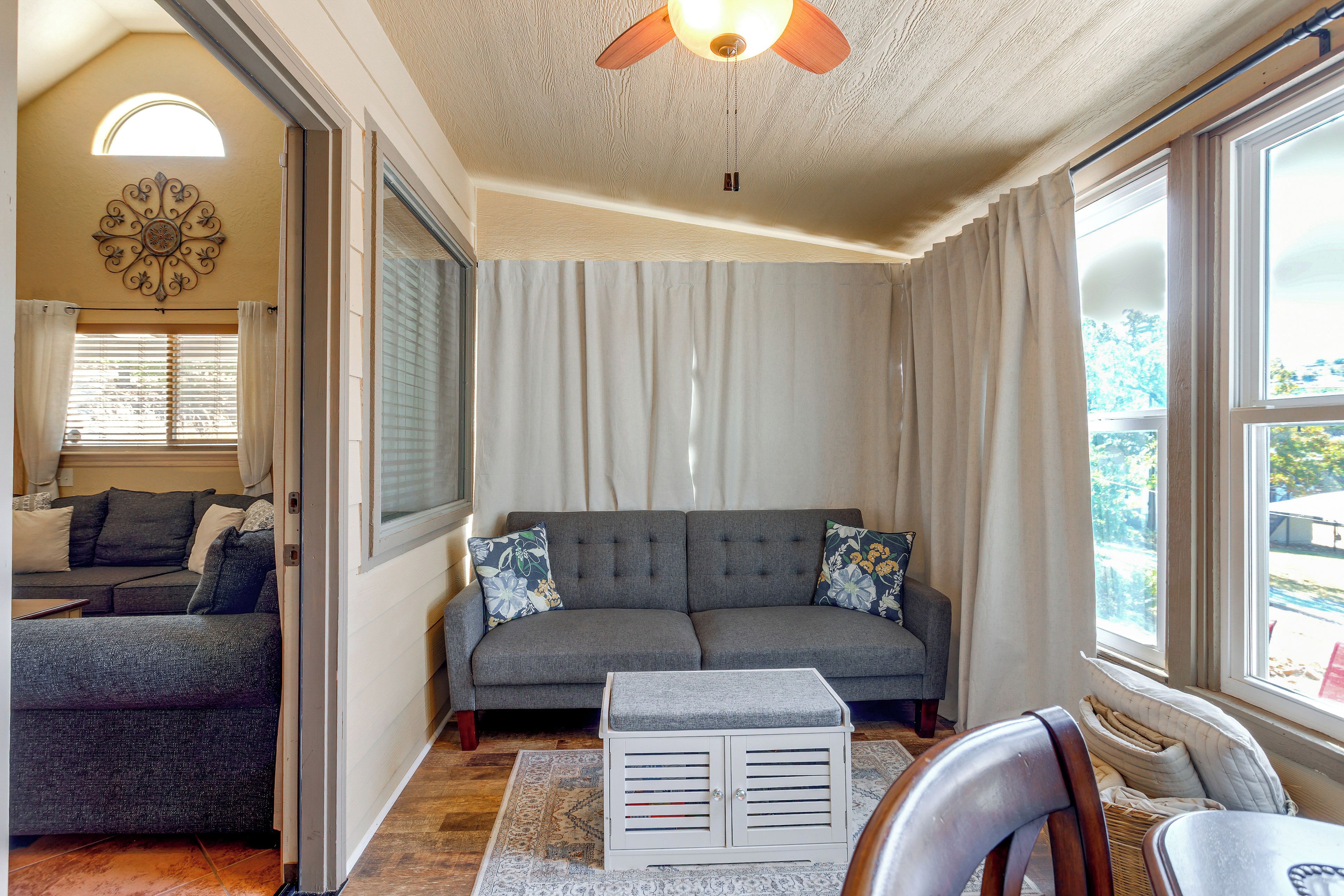 A living room with a grey sofa, a patterned rug, and a ceiling fan.