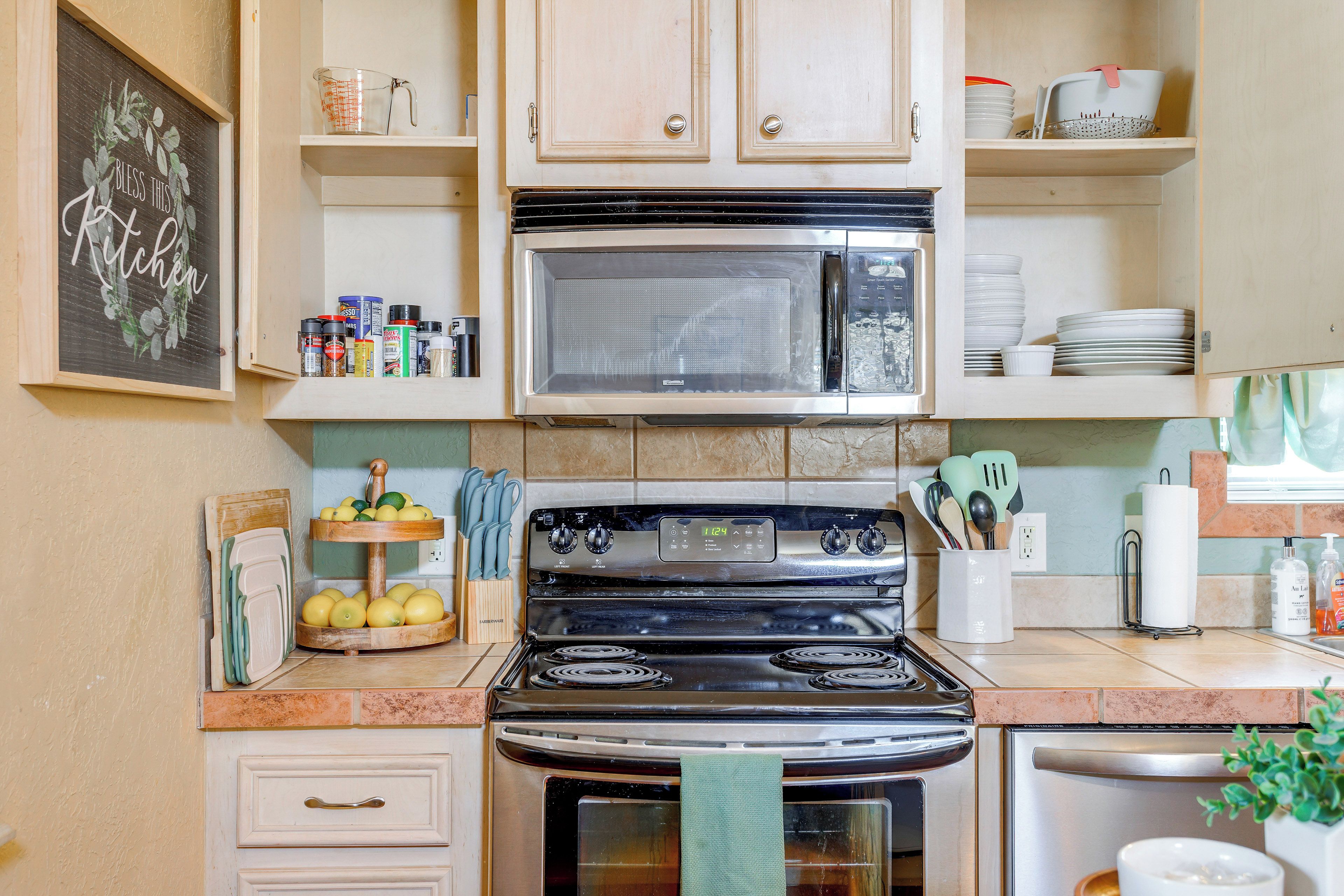 A kitchen with a stove, oven, microwave, and various kitchen utensils.