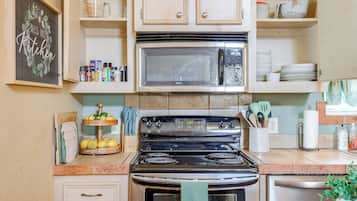 A kitchen with a stove, oven, microwave, and various kitchen utensils.
