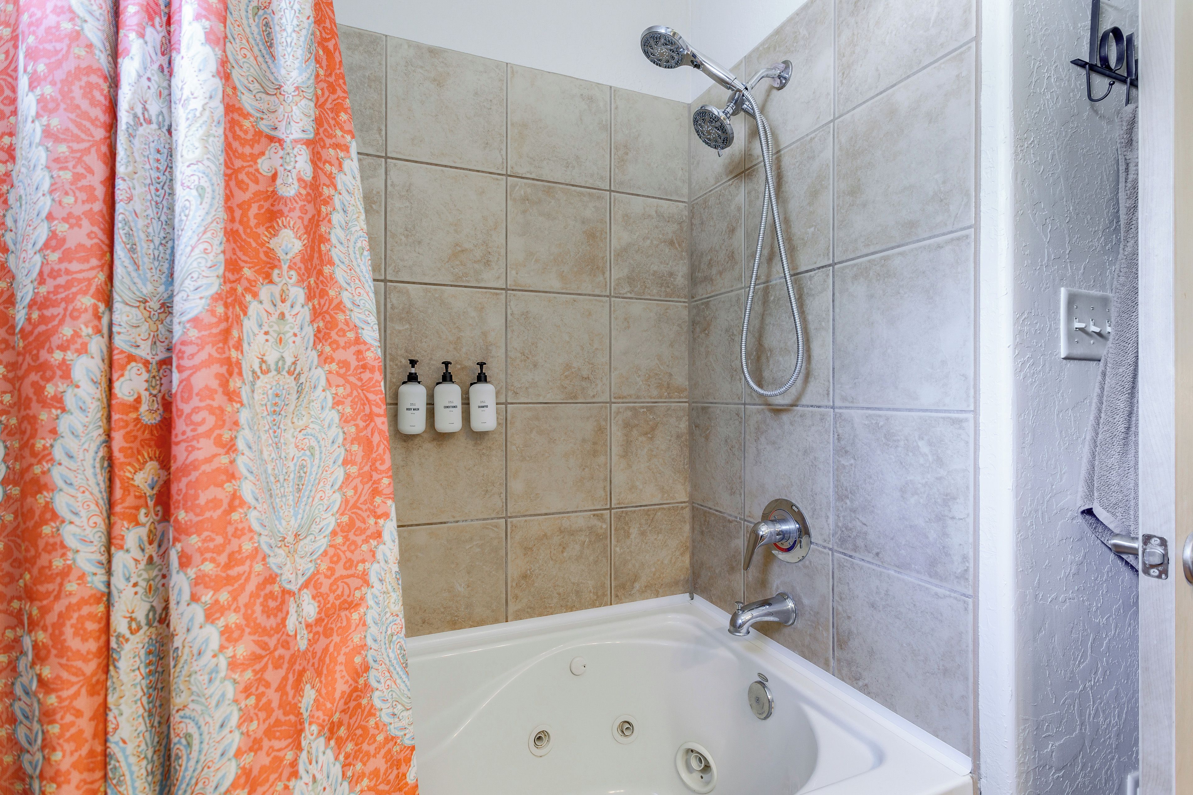 A bathroom with a shower, a bathtub, and three bottles of toiletries.
