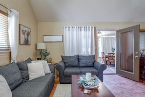 A living room with two grey sofas, a coffee table with a candle and flowers, a lamp, and a framed sign on the wall. - 1/2 Mi to Lake Lawtonka: Mtn-view Haven! (Medicine Park)