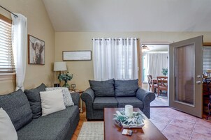 A living room with two grey sofas, a coffee table with a candle and flowers, a lamp, and a framed sign on the wall.