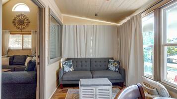 A living room with a grey sofa, a patterned rug, and a ceiling fan.