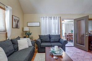 A living room with two grey sofas, a coffee table with a candle and flowers, a lamp, and a framed sign on the wall. - 1/2 Mi to Lake Lawtonka: Mtn-view Haven! (Medicine Park)