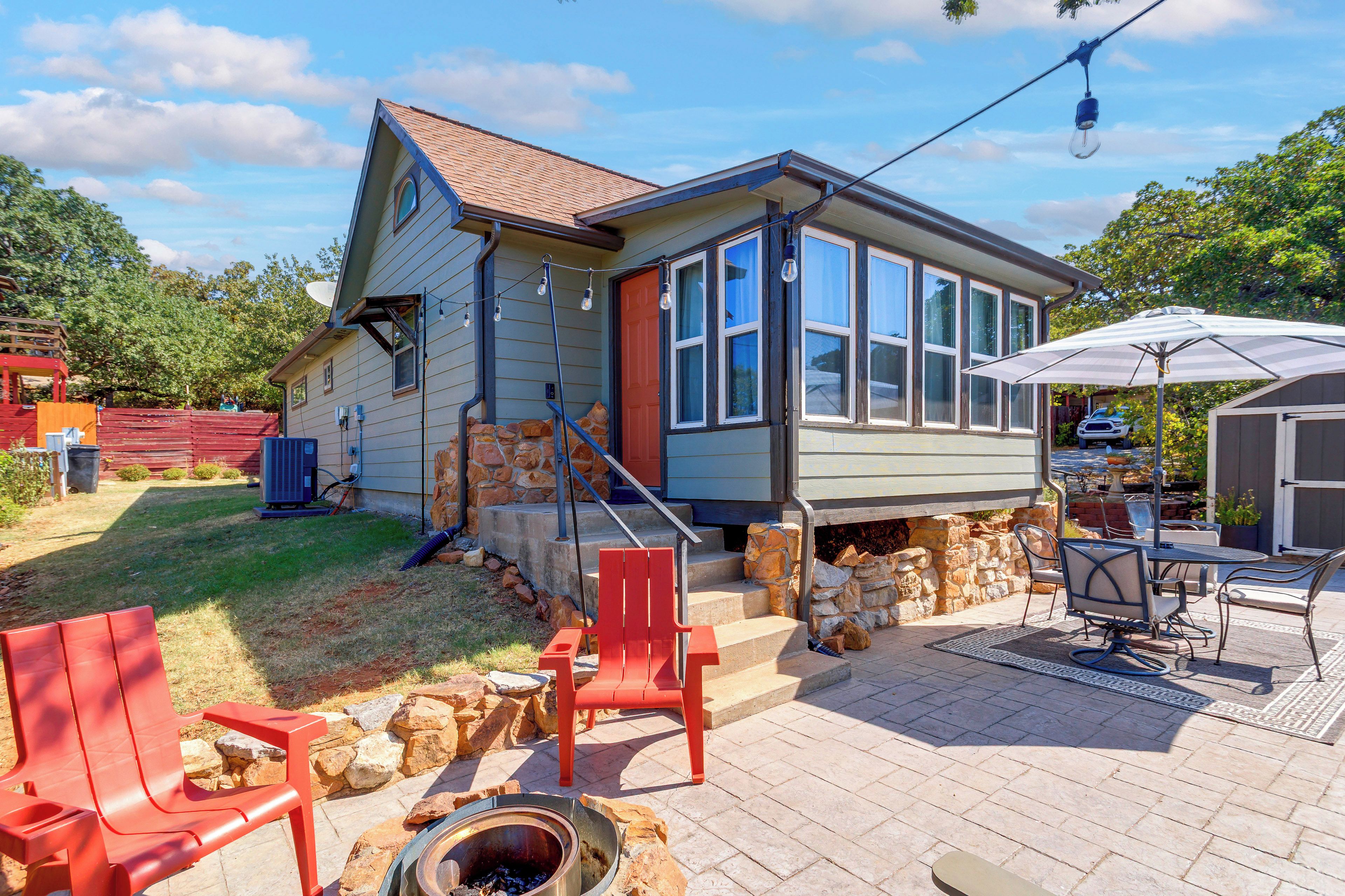 A house with a stone foundation, a red door, and a patio with outdoor furniture.