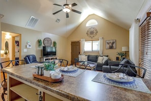 A spacious living area with a high ceiling, a dining table with placemats, a television, and a cozy seating arrangement. - 1/2 Mi to Lake Lawtonka: Mtn-view Haven! (Medicine Park)