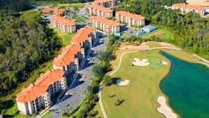 An aerial view of a resort with multiple buildings, a golf course, and a body of water.