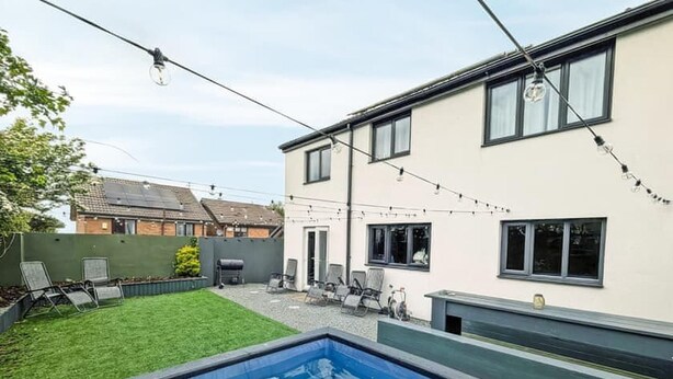 A backyard with a swimming pool, a barbecue area, and string lights. - Eco Friendly White House Sleeps 8 (Colwyn Bay)