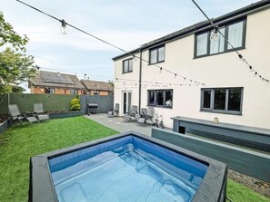 A backyard with a swimming pool, a barbecue area, and string lights. - Eco Friendly White House Sleeps 8 (Colwyn Bay)
