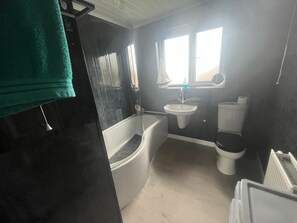A bathroom with a bathtub, sink, toilet, and a window. - Eco Friendly White House Sleeps 8 (Colwyn Bay)