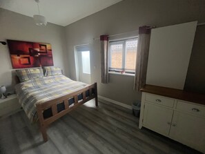Une chambre à coucher avec un lit, une fenêtre avec des rideaux, une table de chevet et une armoire.