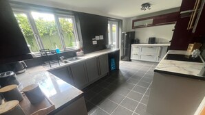 A kitchen with a large window, a refrigerator, and a sink. - Eco Friendly White House Sleeps 8 (Colwyn Bay)