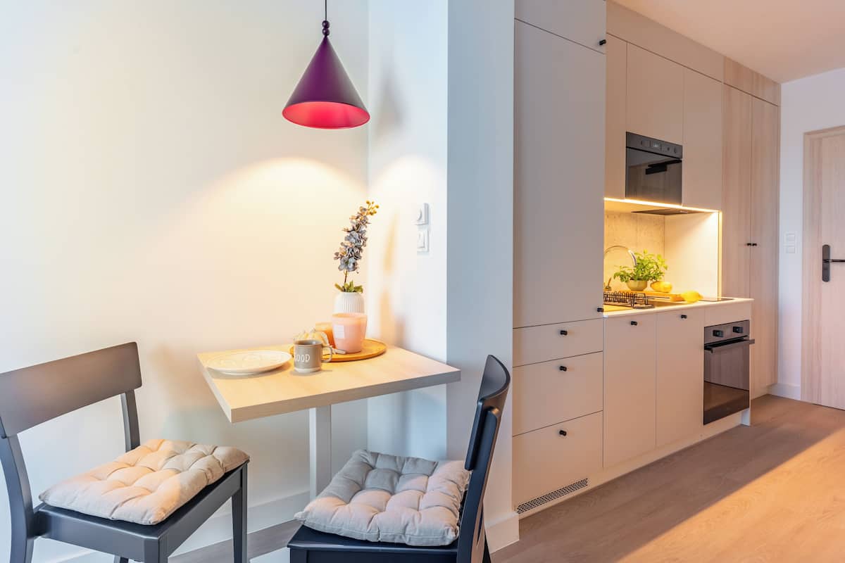 Una cocina moderna con armarios blancos, horno empotrado y una lámpara colgante.