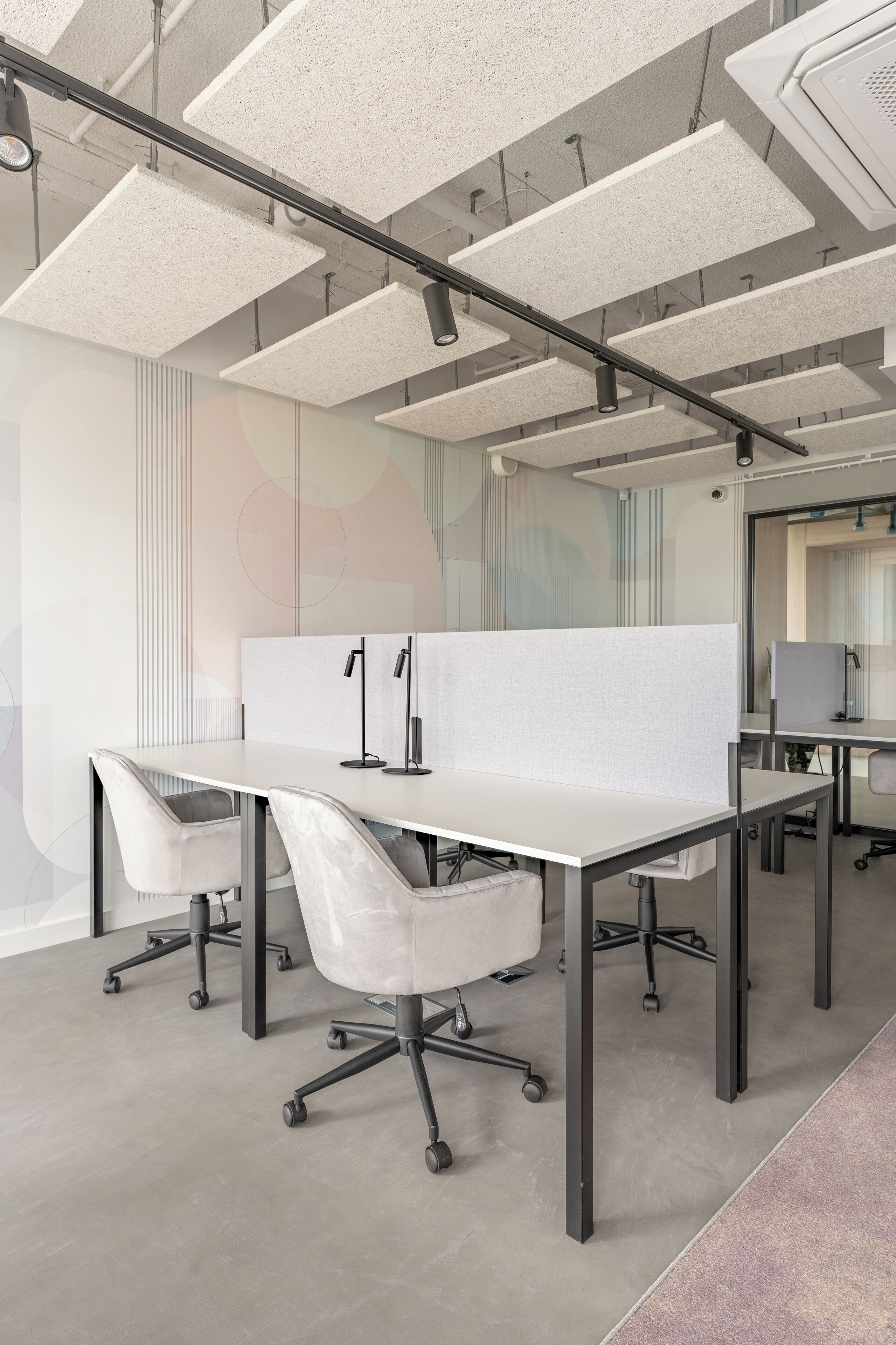 Un espacio de oficina moderno con cubículos, escritorios blancos y sillas ergonómicas.