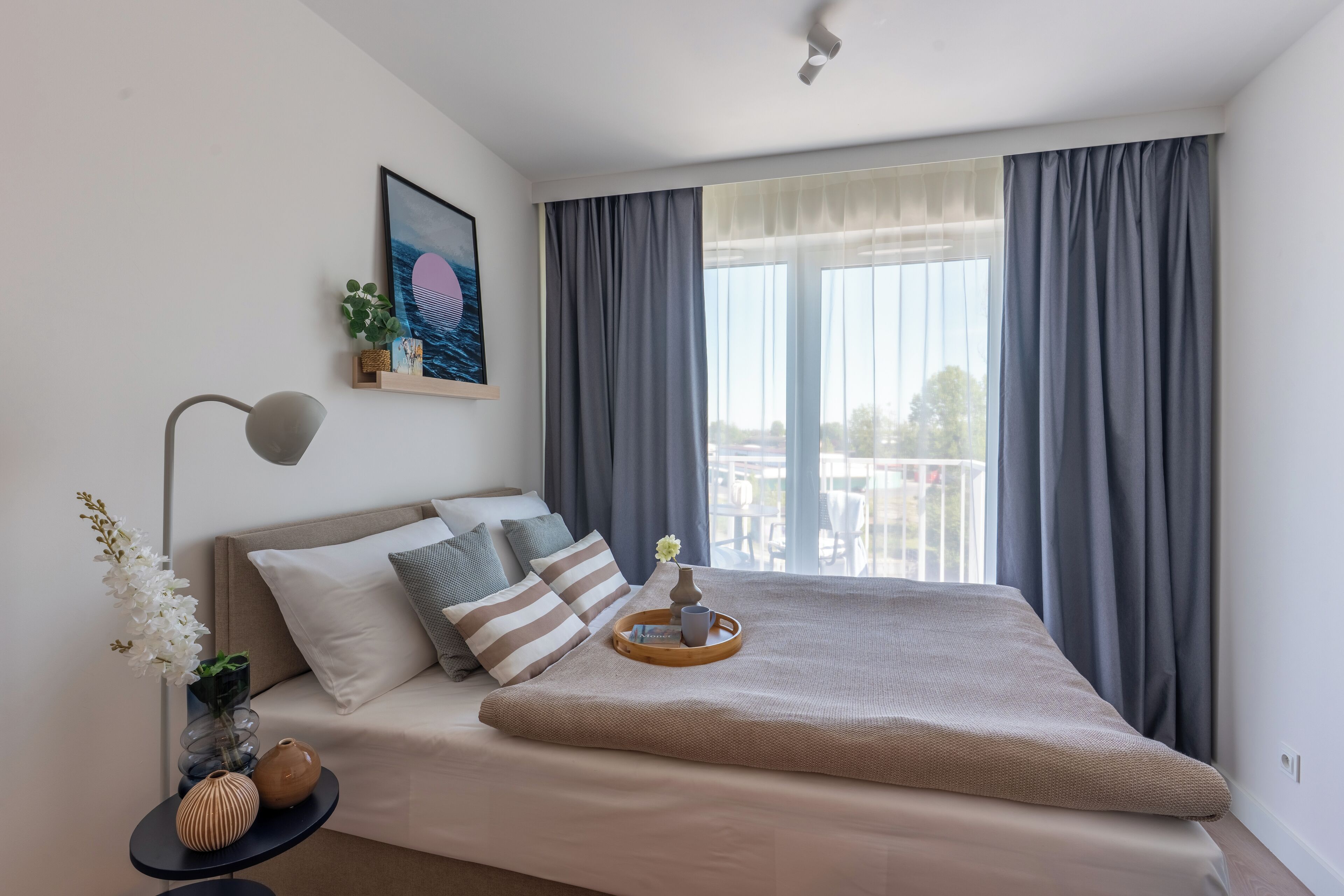 A neatly arranged bedroom with a bed, bedside table, and a window with curtains.