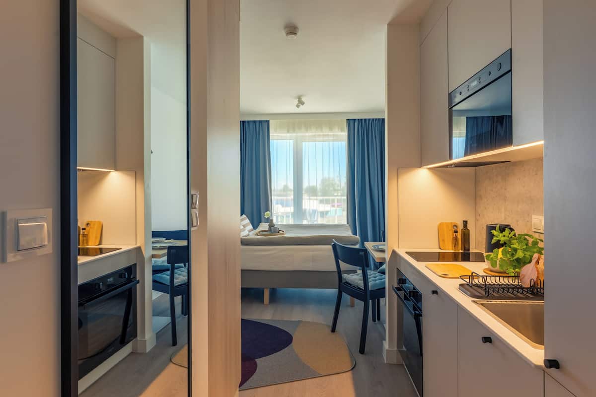 Una habitación de hotel compacta con kitchenette, una cama con vistas y un pequeño comedor.