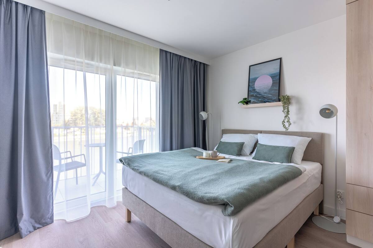 Un dormitorio moderno con una cama grande, vistas al exterior y un cuadro en la pared.