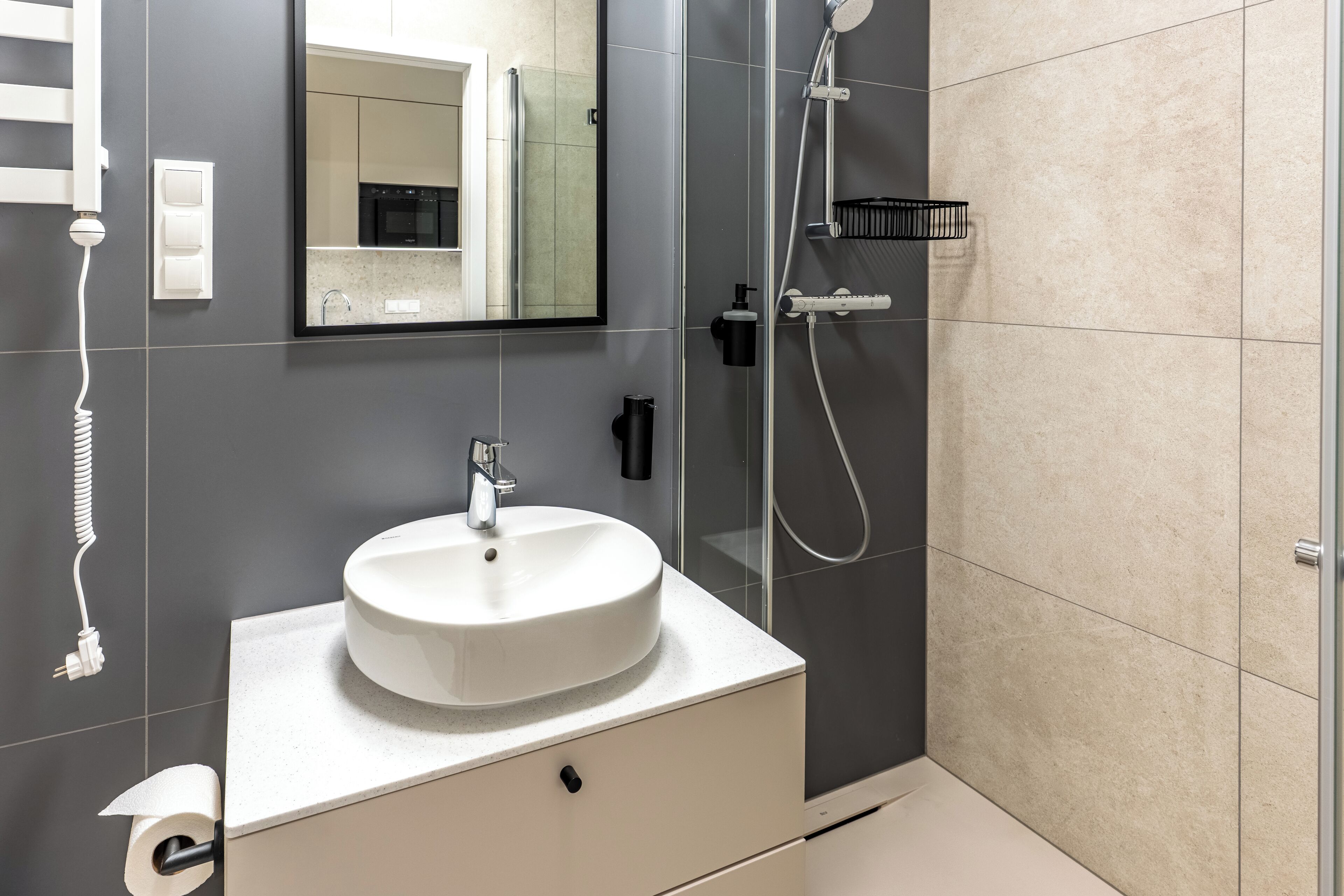 A modern bathroom with a white sink, a mirror, a shower, and a toilet.