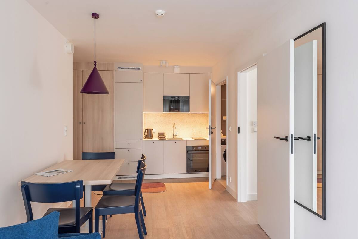 Una cocina moderna con armarios de madera, horno empotrado y una lámpara colgante.
