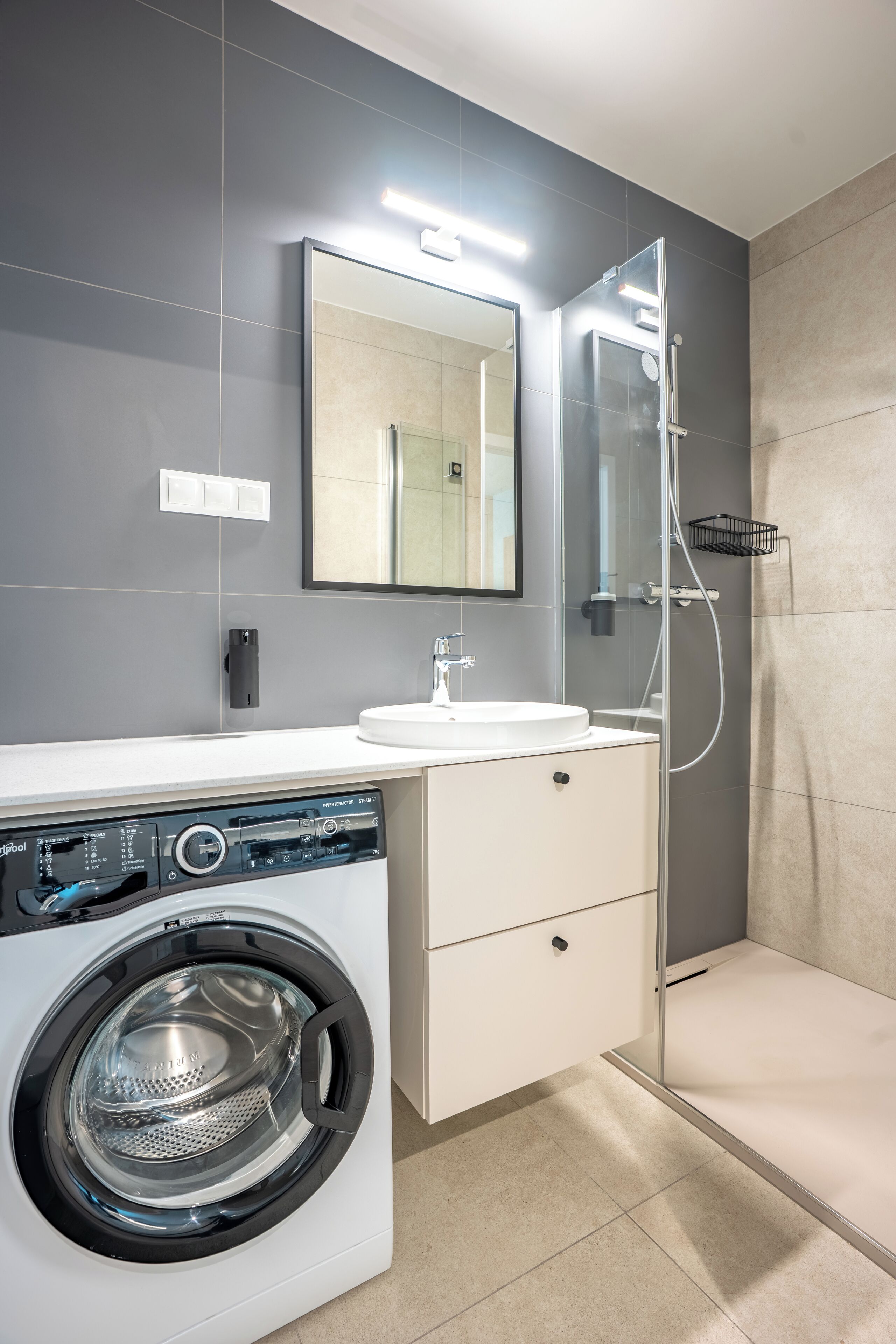 Ein modernes Badezimmer mit Waschmaschine, Waschbecken und Dusche.
