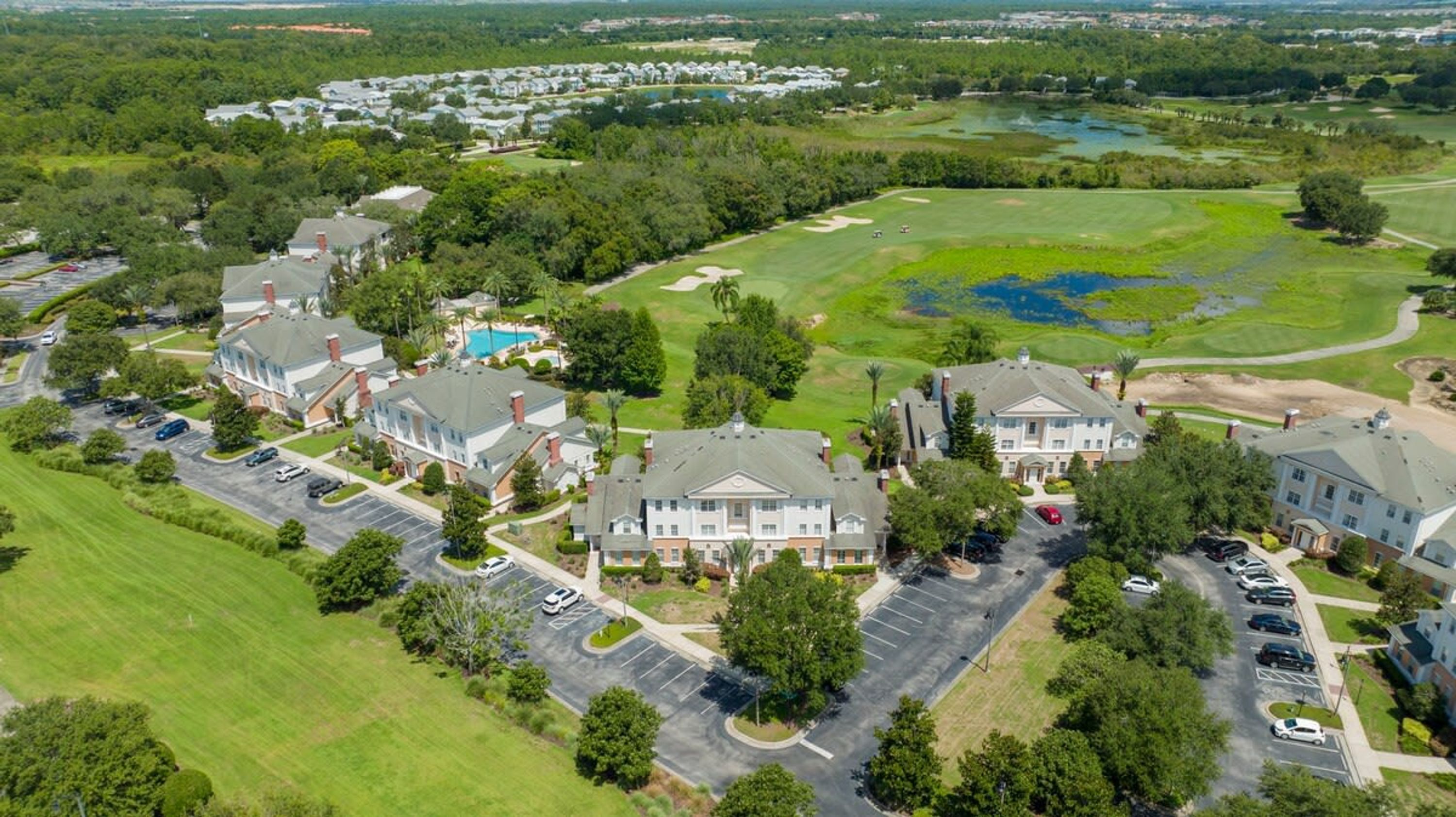 A golf course with a clubhouse and residential buildings.