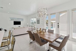Un espace de salle à manger moderne avec une table en bois, des chaises de couleur beige et un lustre décoratif.