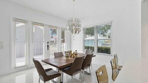 Un espace repas moderne avec une table en bois, six chaises et un lustre sphérique original.
