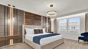 A modern bedroom with a large bed, a chandelier, and a view of the outside through the windows. - Upstay Theme Rooms and Arcade Games Plus Private Pool (Clermont)