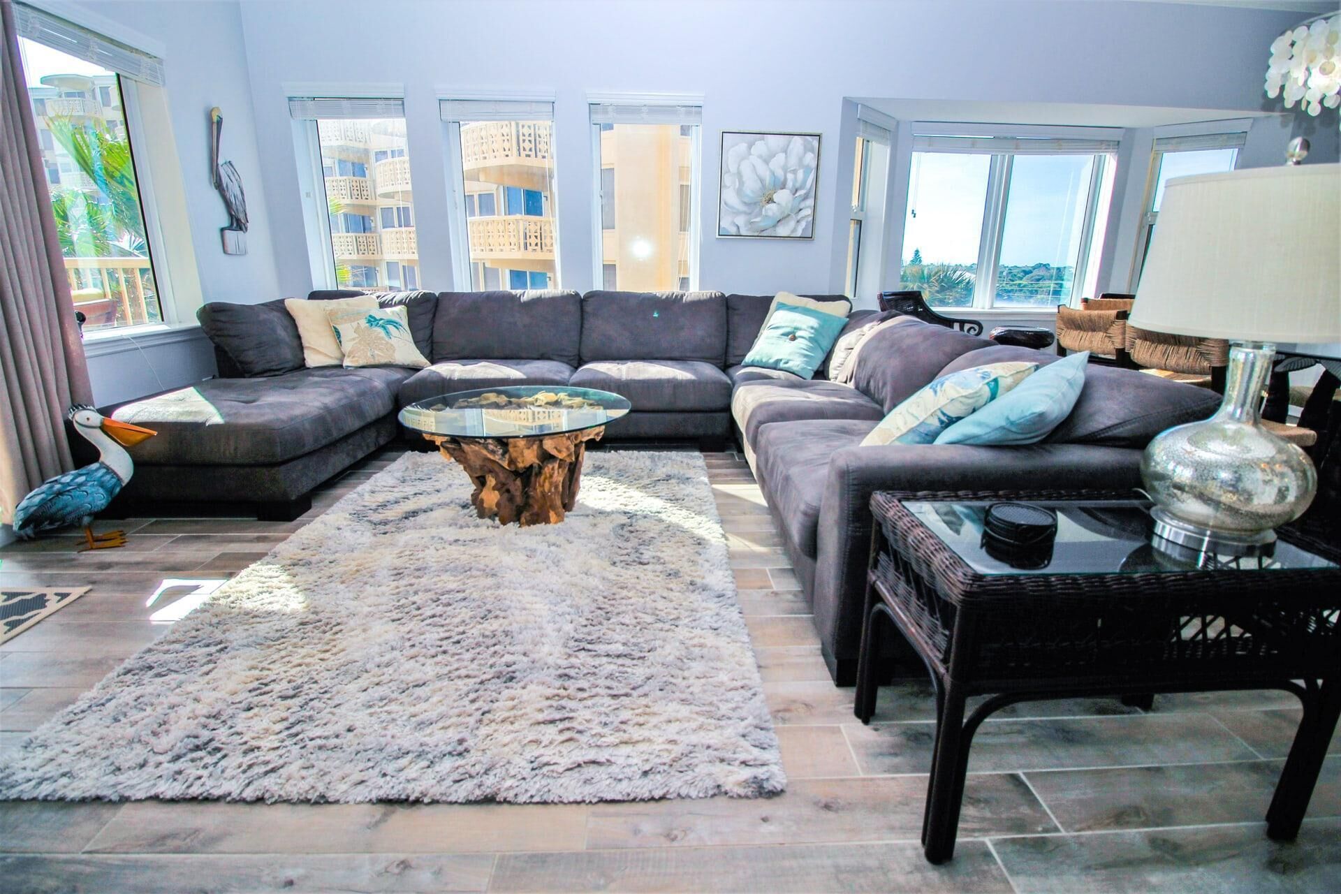 A modern living room with a sectional sofa, a round coffee table, and a large window offering a view of buildings.