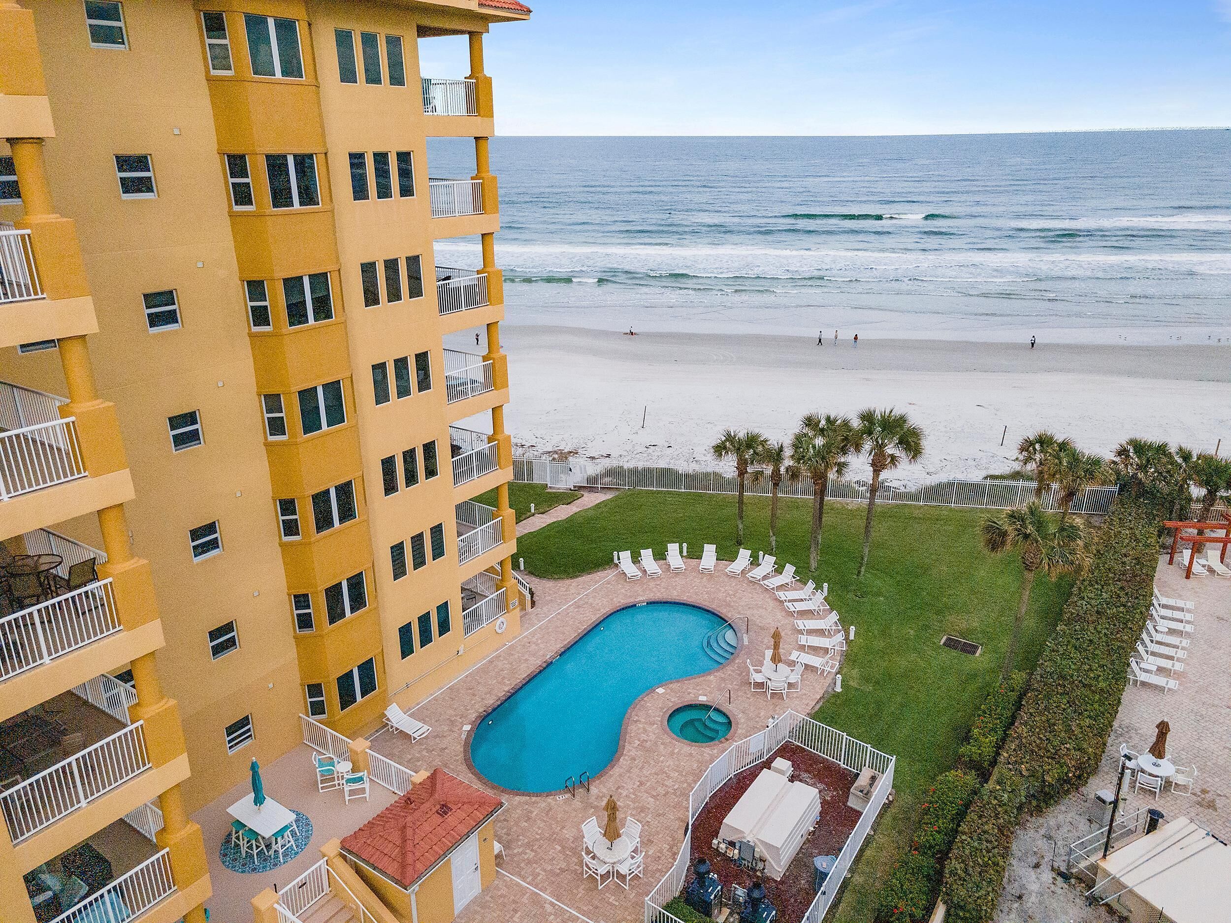 A hotel with a pool, beach view, and multiple balconies.