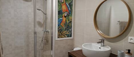 A modern bathroom with a glass-enclosed shower, a white sink, a toilet, and a wooden vanity.