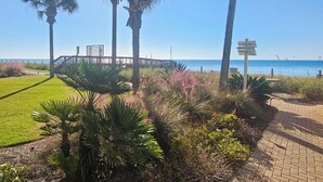 A pathway leading to a beach area with palm trees and a sign indicating nearby amenities like a gym and rental pools. - Sandy Key 123:  2 BR / 2 BA Gulf Front Condo in Perdido Key, FL  Sleeps 6 (Pensacola)