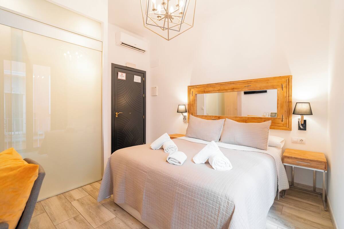 A hotel room with a bed, a wooden headboard, a nightstand, a lamp, and a mirror.